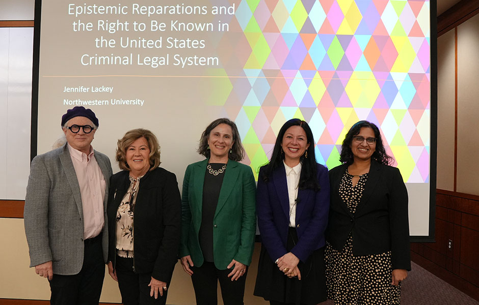 Five people standing in a line smiling in front of a projection screen displaying the presentation title, "Epistemic Reparations and the Right to Be Known in the United States Criminal Legal System" by Jennifer Lackey from Northwestern University.
