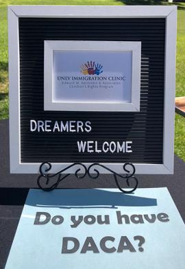 Photo of sign and and blue paper on a table displaying the UNLV Immigration Clinic logo and reads Dreamers Welcome - Do you have DACA?