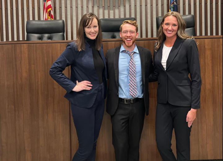 3 student attorneys pose in courtroom