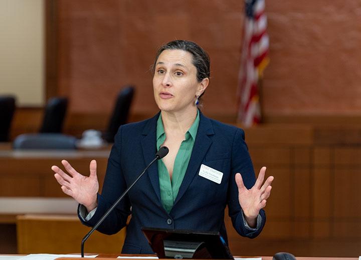 women speaks into microphone with her hands raised