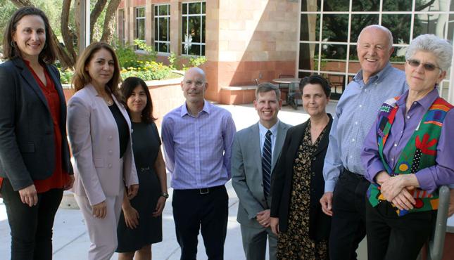 eight people stand in line and smile at the camera
